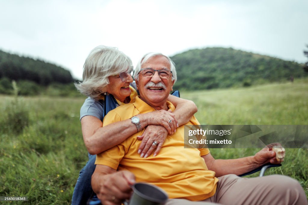 Affectionate senior couple bonding while camping together at forest