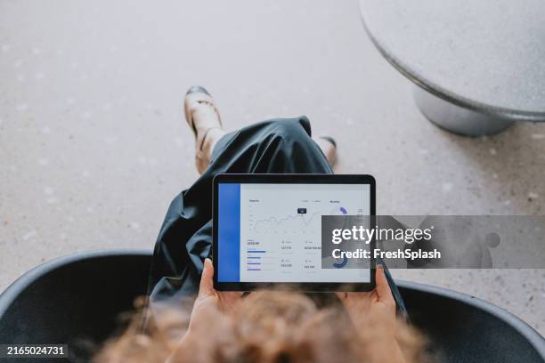 frau, die daten auf einem tablet in einem modernen büro analysiert - geld verdienen stock-fotos und bilder