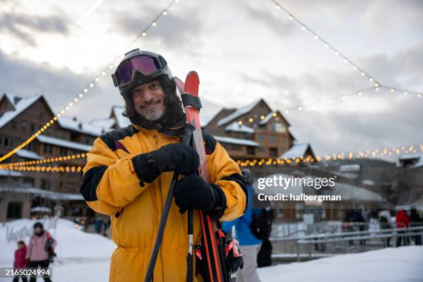 smiling man cradling his skis and smiling at camera - skier portrait stock pictures, royalty-free photos & images