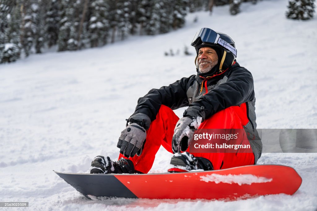 Grinning Older Snowboarder Taking a Rest