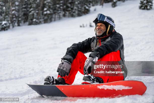 grinning older snowboarder taking a rest - winter sport stock pictures, royalty-free photos & images