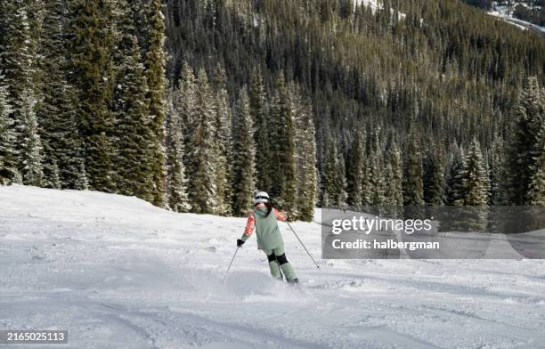 woman in green carving down steep ski run - woman skier stock pictures, royalty-free photos & images