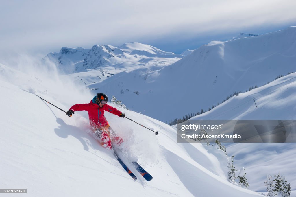 Skier skis down slope through fresh powder snow
