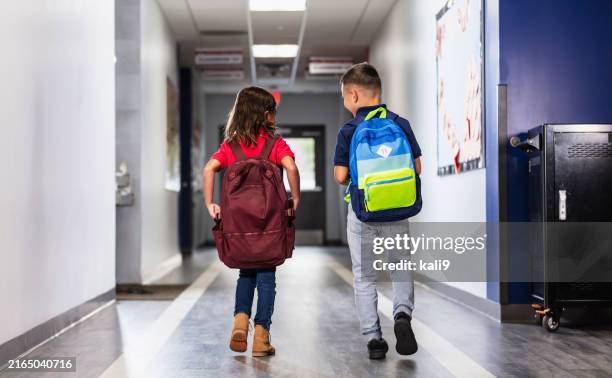 two multiracial elementary students in school hallway - somente crianças imagens e fotografias de stock