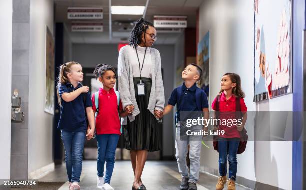 grundschullehrerin mit vier kindern auf dem flur - schulleiter stock-fotos und bilder