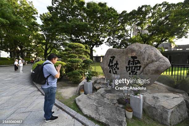 Man pray in front of the Atomic Bomb Dome as people prepare for the Peace Message Lantern Floating Ceremony at the Hiroshima Peace Memorial Park to...