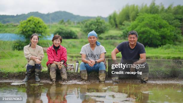ritratto di famiglia asiatica che si prende una pausa dal lavoro sulla risaia e riposa insieme mentre mangia il cibo nella fattoria della risaia - satoyama-scenery foto e immagini stock