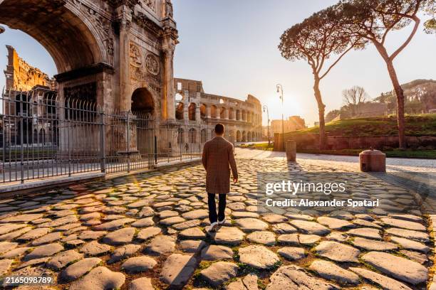man walking to coliseum at sunrise, rear view, rome, italy - roman forum rome stock pictures, royalty-free photos & images