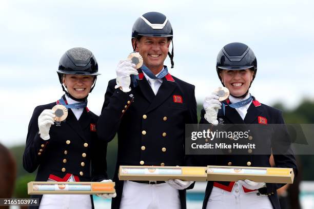 Bronze medalists Charlotte Fry, Carl Hester and Becky Moody of Team Great Britain pose for a photo during the medal ceremony for the Dressage Team...