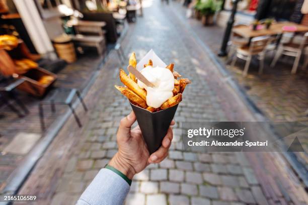 eating french fries with mayonnaise on the street, personal perspective view - batata frita francesa imagens e fotografias de stock