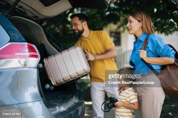 genitori che aiutano il figlio a imballare l'auto per l'avventura di viaggio in famiglia - imballare foto e immagini stock