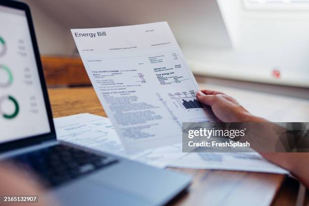 person reviewing energy bill at home on a laptop - eletricidade imagens e fotografias de stock