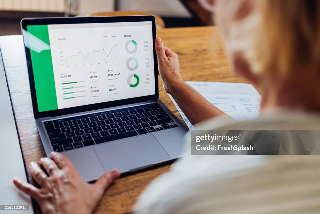 Person Analyzing Data Reports On Laptop Screen at Desk