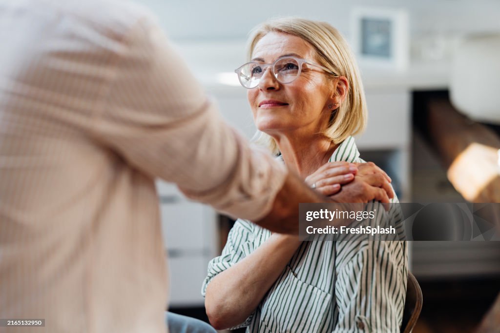 Senior Woman Supported by Male Friend in Modern Home Interior