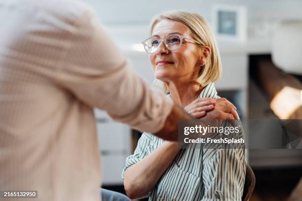 senior woman supported by male friend in modern home interior - cuidar se imagens e fotografias de stock