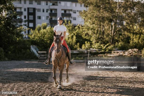 young woman enjoys equestrian activity on horse in natural outdoor setting during bright daytime - dressage stock pictures, royalty-free photos & images