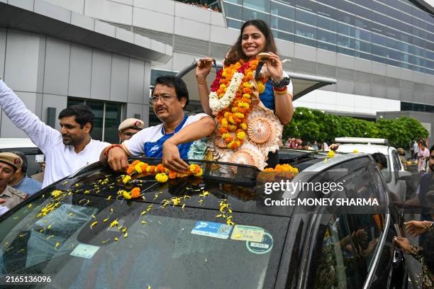 India's shooter Manu Bhaker poses with her coach Jaspal Rana, as she arrives at Indira Gandhi International Airport in New Delhi on August 7 after...