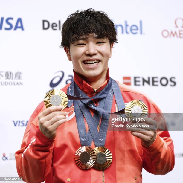 Shinnosuke Oka of Japan shows off on Aug. 6 three gold medals he won in the men's gymnastics individual all-around, horizontal bar and team events...