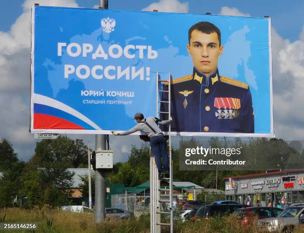 Worker installs a military propaganda billboard on the highway with picture of Russian Armed Forces' Senior Leutenant Yuri Kochish, who took part in...