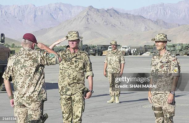 German Air Force Colonel Uwe Aherns salutes German Brigadier General Werner Freers , as German Colonel Martin Schelleis looks on during a ceremony...