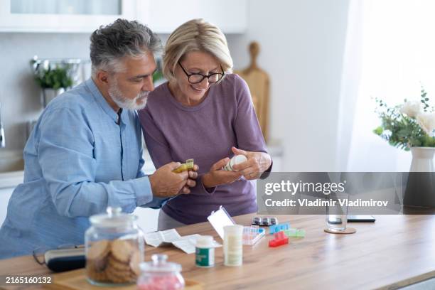 älteres paar, das zu hause medikamente einnimmt - tablettenschachtel stock-fotos und bilder