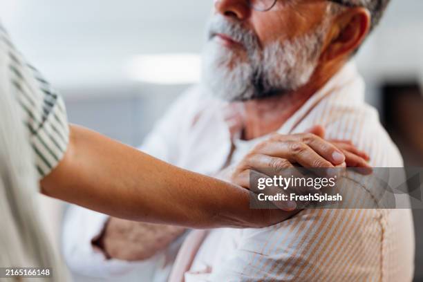 supportive hand on elderly man's shoulder in comforting gesture - mantelzorg stockfoto's en -beelden