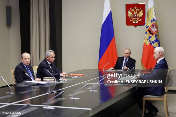 In this pool photograph distributed by Russian state owned Sputnik agency, Russia's President Vladimir Putin flanked by Russia's Defence Minister...