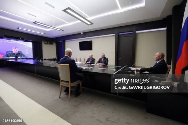 In this pool photograph distributed by Russian state owned Sputnik agency, Russia's President Vladimir Putin flanked by Russia's Defence Minister...