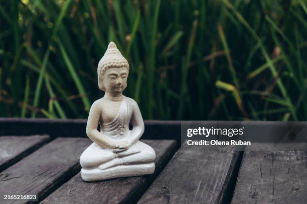 a meditating buddha little figurine on dark planks. - spirituelle erleuchtung stock-fotos und bilder