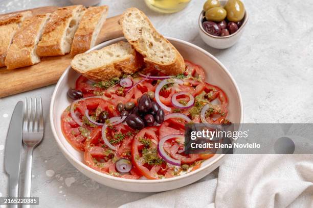 tomatoes salad with pesto sauce, spices , black olives and olive oil. elegant serving healthy vegetable salad - carpaccio stock-fotos und bilder