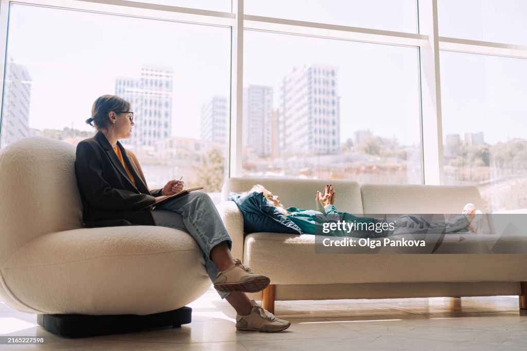 Two women sitting in armchairs and talking. Female coach, psychotherapist, psychologist, advisor and patient, client. Psychotrapy