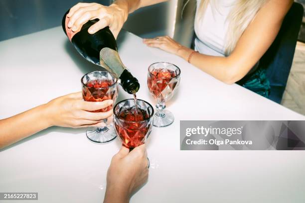 unrecognizable female friends celebrate and drink red sparkling wine - hand pouring wine stock pictures, royalty-free photos & images