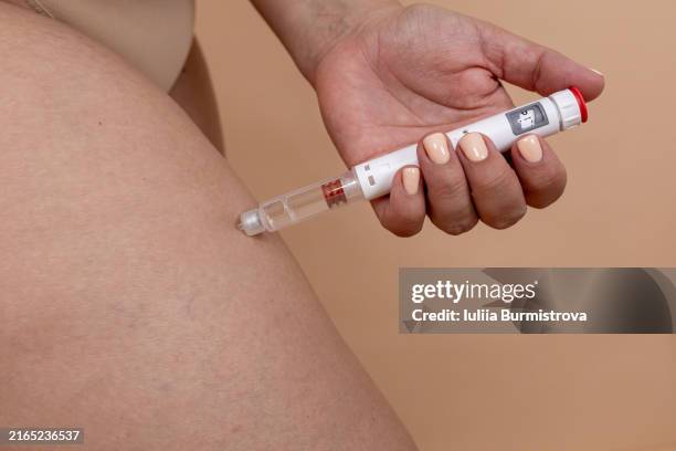 living with diabetes. a woman make insulin injection in leg with syringe - cholesterol stockfoto's en -beelden