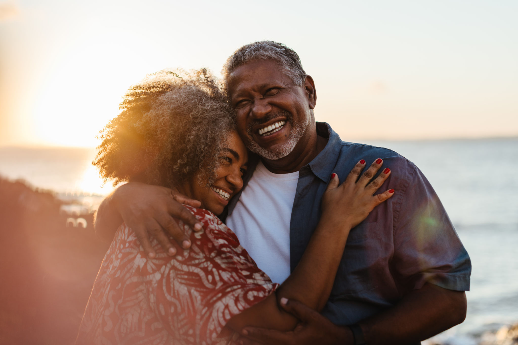 Elderly pair embracing at sunset, sharing joy and love by the seaside Elderly pair embracing at sunset, sharing joy and love by the seaside