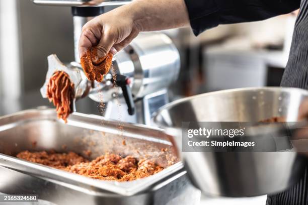the cook prepares the ground meat by seasoning it with spices, salt and ground pepper. - ground beef stock pictures, royalty-free photos & images