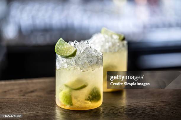 sweet and refreshing caipirinha national cocktail from brazil made with lime,ice, sugar, and a sugarcane liquor on barcounter with crushed ice. - caipirinha foto e immagini stock