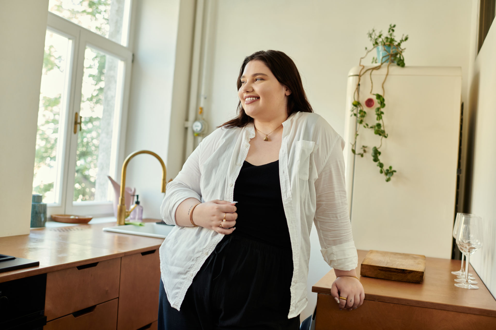 Joyful Plus Size Woman Smiling at Home in Modern Kitchen During Bright Daytime Joyful Plus Size Woman Smiling at Home in Modern Kitchen During Bright Daytime