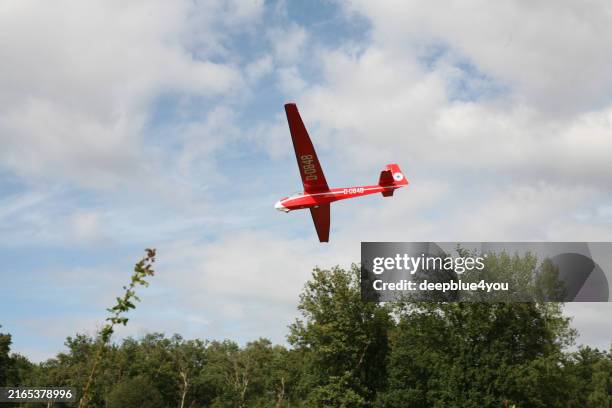 a red motor glider on final approach at boberg airfield, located in the boberger niederung nature reserve - zweefvliegtuig stockfoto's en -beelden