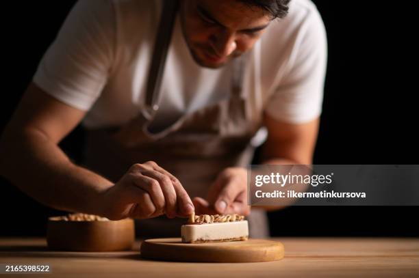 ein männlicher konditor backt einen kuchen mit erdnüssen - kuchen dekorieren stock-fotos und bilder
