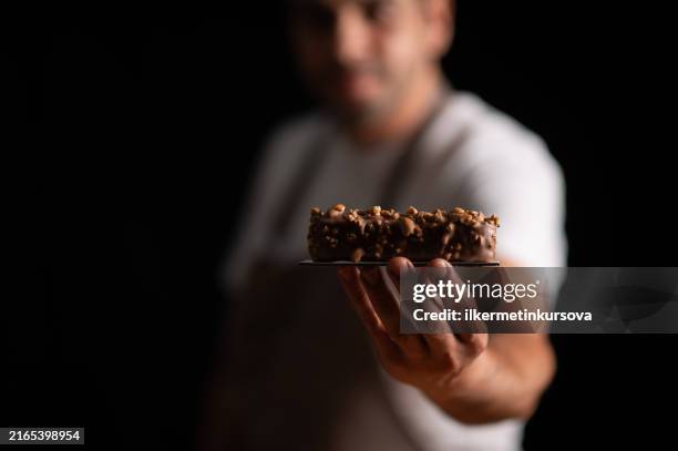 a male pastry chef holding a peanut cake - confectioner stock pictures, royalty-free photos & images