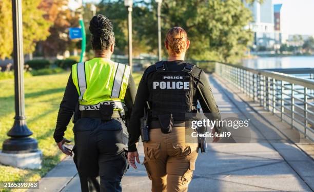 two policewomen patrolling a city park on foot - police woman stock pictures, royalty-free photos & images