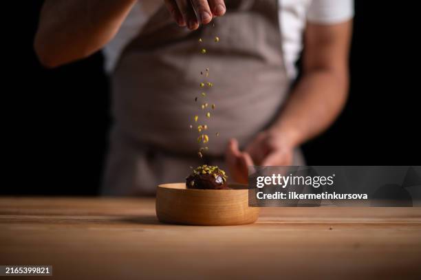 um chef confeiteiro derramando pistache em profiteroles - sobremesa - fotografias e filmes do acervo