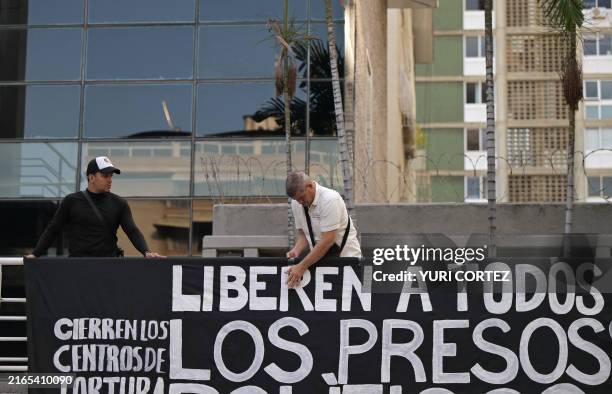 Man hangs a banner demanding freedom for political prisoners arrested during protest following the contested re-election of Venezuelan President...