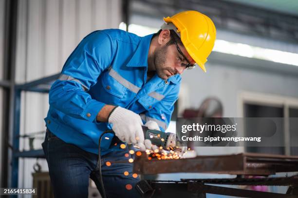 workers were grinding steel inside the workshop until it sparked. - obrero-siderúrgico fotografías e imágenes de stock