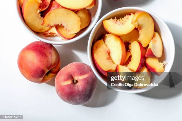 peaches and bowls of sliced fruits against a white background - persika bildbanksfoton och bilder
