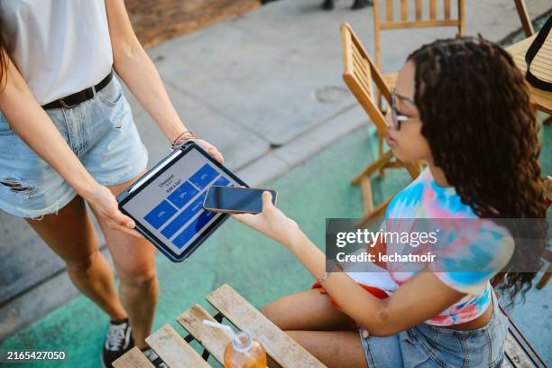 young woman pays contactless in a cafe in venice, california - gratuity stock pictures, royalty-free photos & images