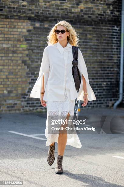 Guest wears white button shirt, black Bottega Veneta bag, white laced skirt with slit outside A. Roege Hove during the Copenhagen Fashion Week SS25...