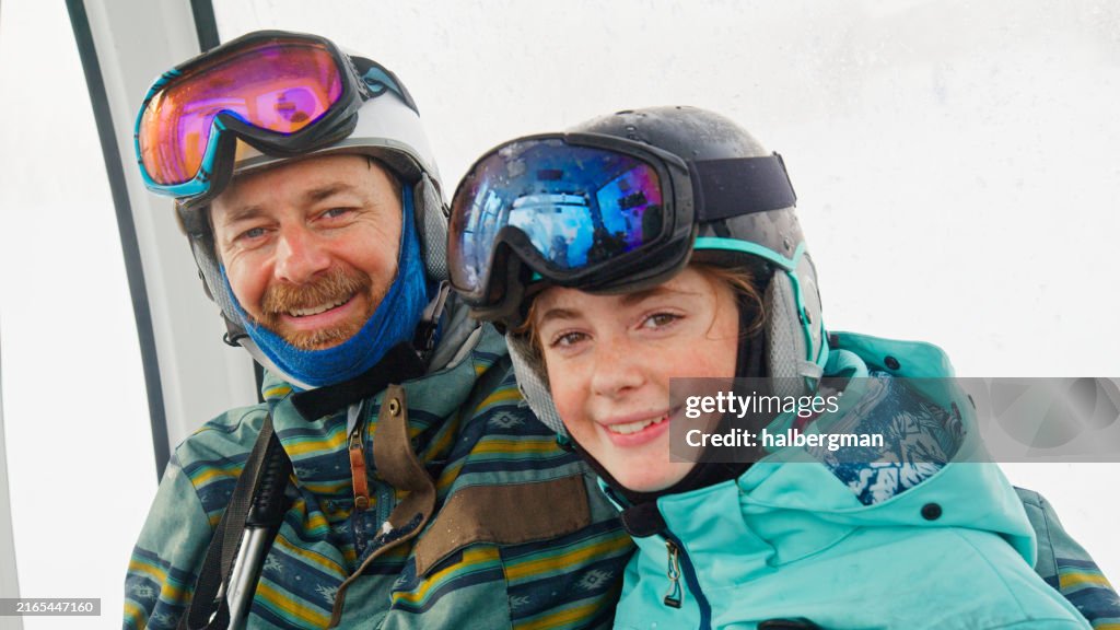 Skiing Father-Daughter Duo Smiling at Camera Inside Gondola