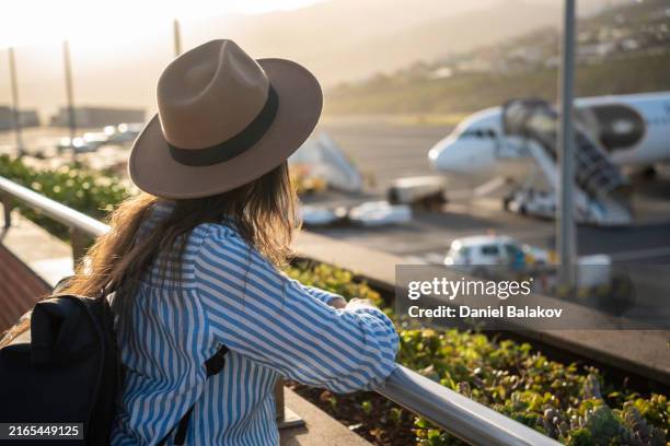 air travel journey. woman at airport looks at airplane at sunset. - funchal stock pictures, royalty-free photos & images