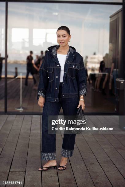 Benthe Liem wears navy blue jeans from Dior, white tank top and matching navy blue jacket and Dior bag outside Forza Collective show during the...